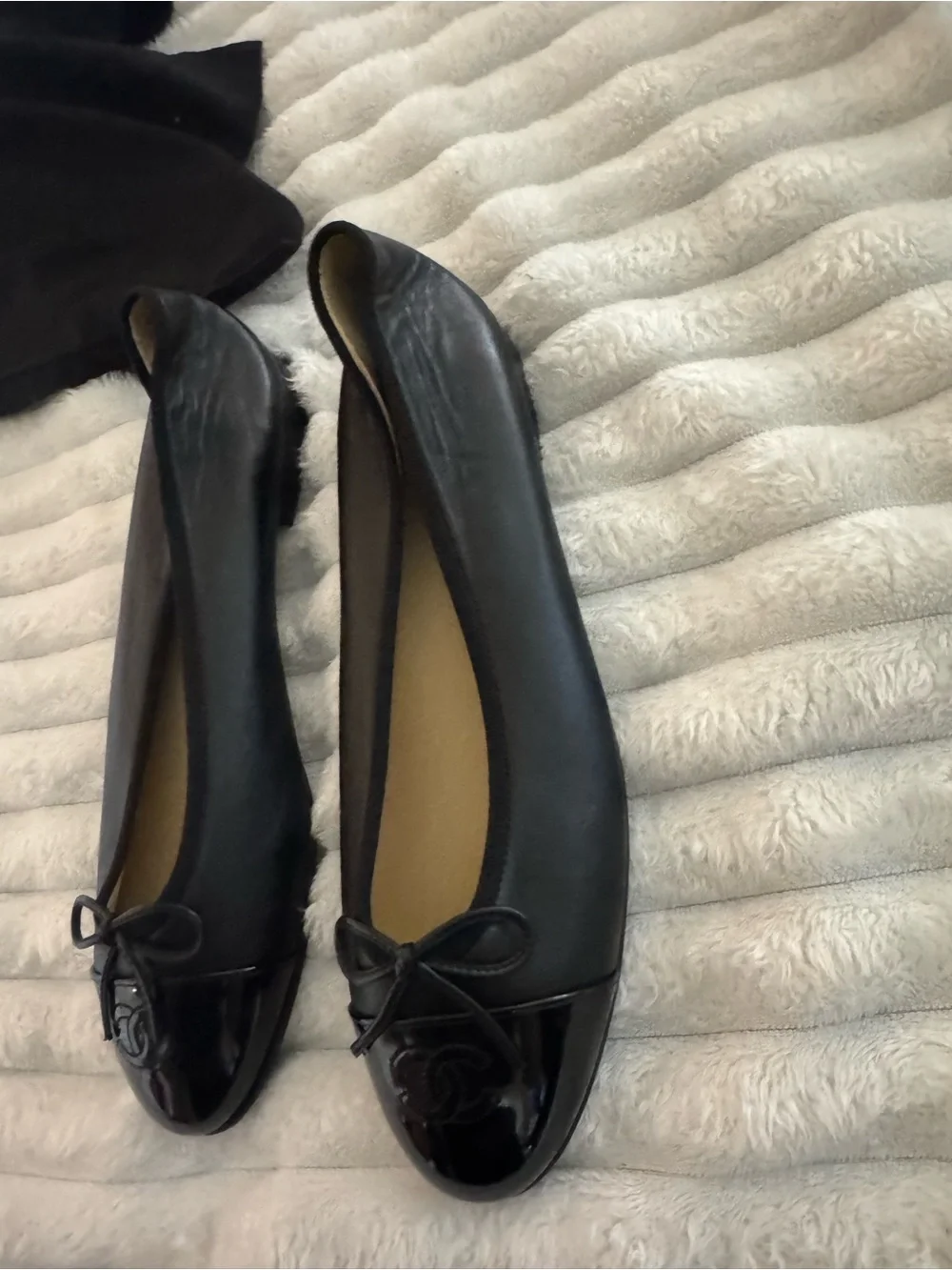CHANEL Black Leather Ballet Flats with Patent Cap Toe and Bow Accent